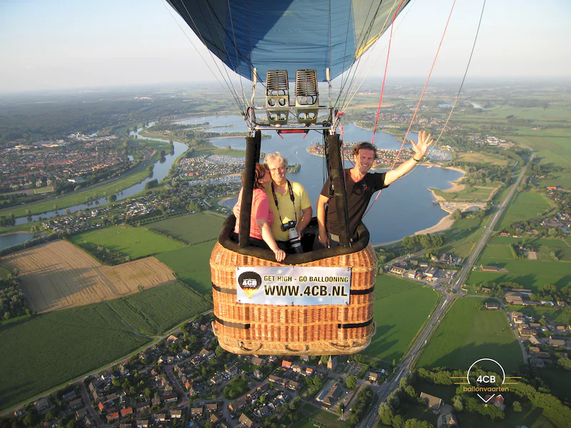 Luchtballon met 3 passagiers tijdens een privéballonvaart boven rivieren, velden en dorpen in Gelderland.